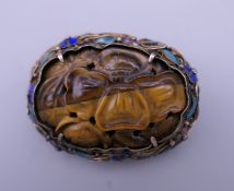 A Chinese enamel decorated silver mounted tigers eye brooch. 4.5 cm wide.