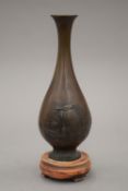 A 19th century Japanese bronze vase on a wooden stand. The vase 17.5 cm high.