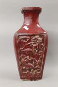 A Chinese red ground pottery vase on a carved wooden base. 59.5 cm high overall.