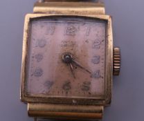 An 18 K gold cased watch on a rolled gold strap. 12.4 grammes total weight.