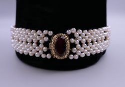 A garnet and unmarked gold clasp mounted cultured pearl necklace. 39 cm long.
