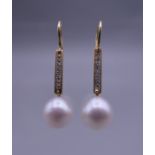A pair of unmarked 18 K gold diamond and pearl earrings. 3.25 cm high.