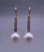 A pair of unmarked 18 K gold diamond and pearl earrings. 3.25 cm high.