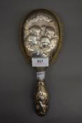 A silver backed brush decorated with cherubs.