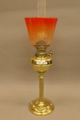 A Victorian brass oil lamp with orange glass shade. 73.5 cm high overall.