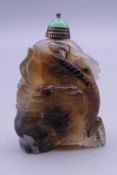 A carved mottled agate snuff bottle with large dragon to front with green jade stopper. 5.5 cm high.