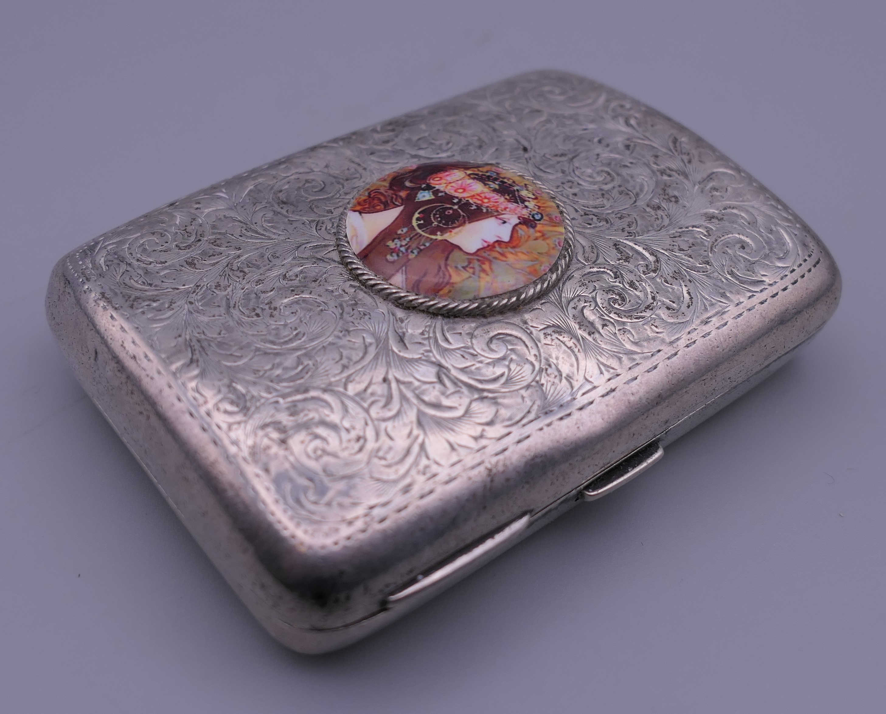 A silver cigarette case depicting a girl. 6 cm wide.