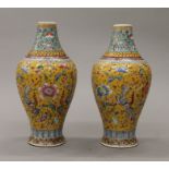 A pair of Chinese porcelain yellow ground famille rose vases, hand painted with flowers,