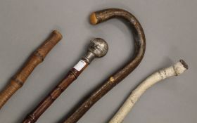 A bamboo cane swagger stick, a silver topped walking stick and two other sticks.