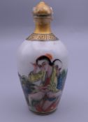A porcelain snuff bottle decorated with an erotic scene. 9 cm high.