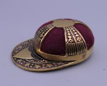 A jockey cap form pin cushion. 4 cm wide.