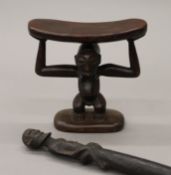 An African tribal carved wooden head rest and a sceptre. The latter 49 cm long.