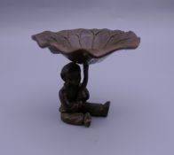 A bronze figure of a boy holding a lily pad. 5.5 cm high.