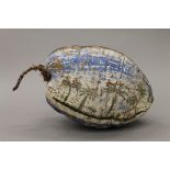 A painted and posted coconut husk set with a postage stamp. 27 cm long.