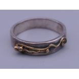 A silver ring with unmarked gold decoration. Ring size O/P.