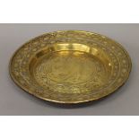 A 17th/18th century brass alms dish decorated with a man and a dragon. 48.5 cm diameter.