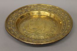 A 17th/18th century brass alms dish decorated with a man and a dragon. 48.5 cm diameter.