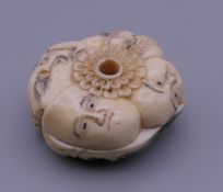 A carved bone roundel carved as faces. 4 cm diameter.