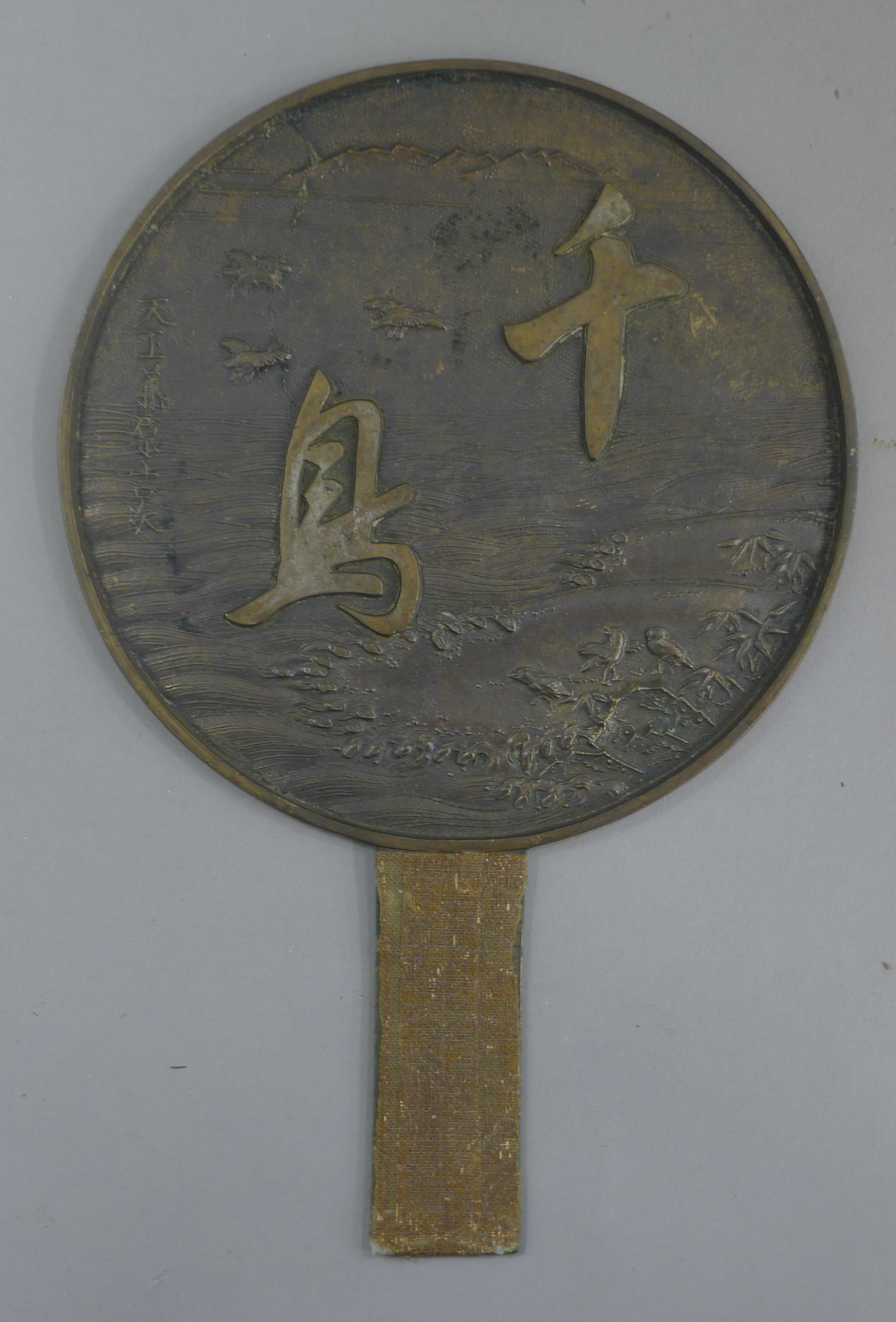 A Chinese bronze hand mirror. 27 cm high.