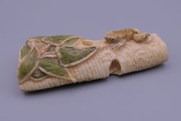 A carved bone netsuke decorated with a frog. 6 cm high.