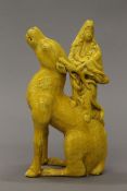 A 19th century Chinese yellow ground pottery model of Guanyin standing on a deer. 26 cm high.