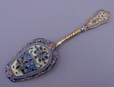 An enamel decorated silver gilt caddy spoon bearing Russian marks. 13 cm long.