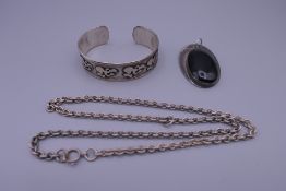 A silver cuff bracelet, a silver pendant and a white metal chain.