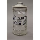 A glass storage jar with a Meredith and Drew biscuit jar lid,