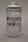 A glass storage jar with a Meredith and Drew biscuit jar lid,