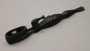 An ebony carving of a laying figure holding a basket, inscribed A.B.92. 49 cm long.