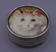 A silver pill box depicting a cat. 2.75 cm diameter.
