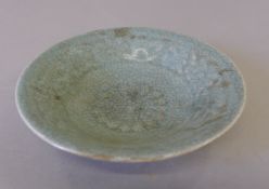 A small celadon dish decorated with calligraphy. 14 cm diameter.