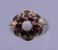 An unmarked 9 ct gold garnet and opal ring. Ring size M. 1.6 grammes total weight.