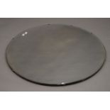 A large circular bevelled mirror. 89 cm diameter.