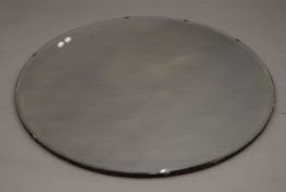 A large circular bevelled mirror. 89 cm diameter.