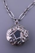 A silver locket on chain. The locket 2 cm diameter.