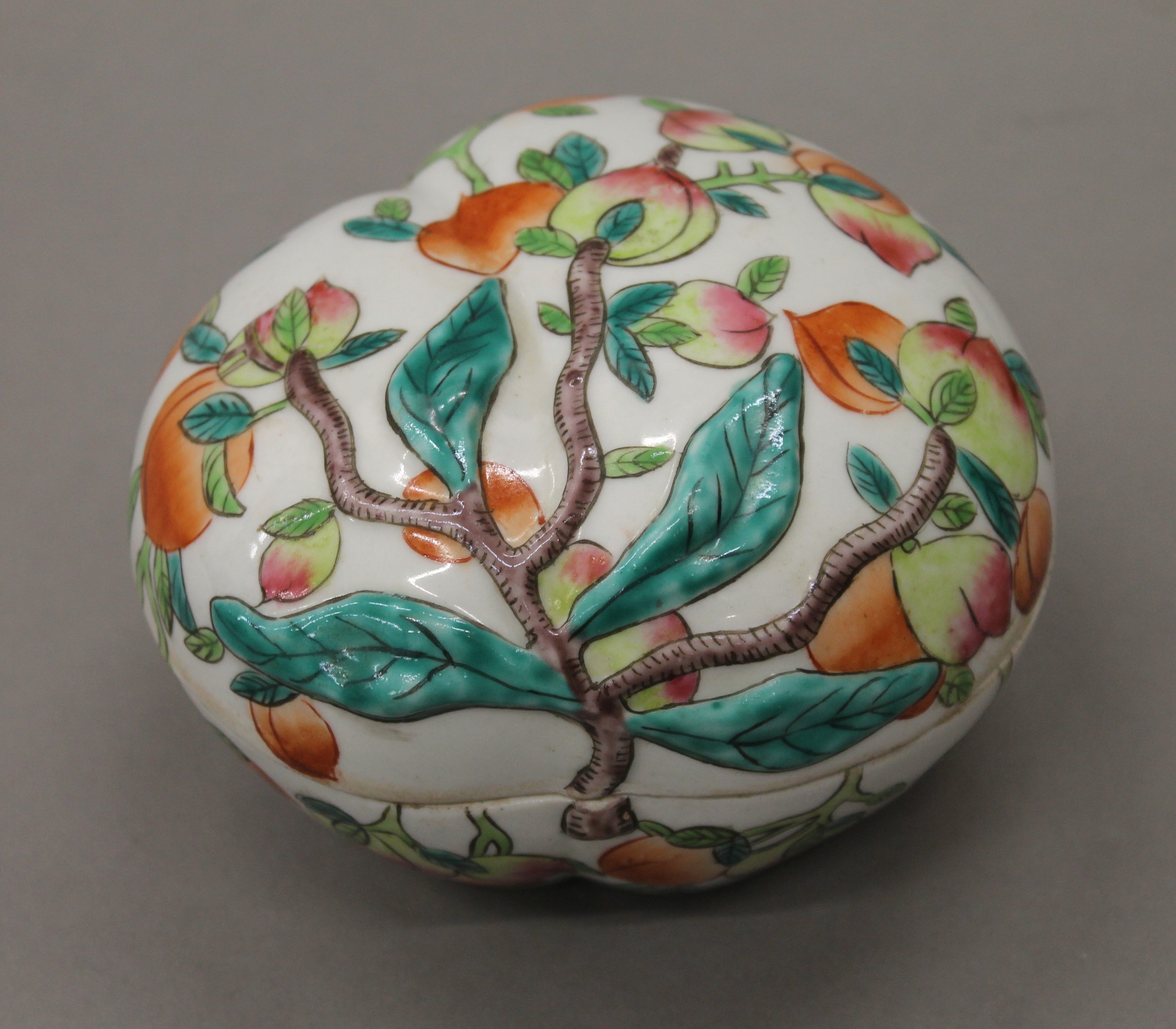 A Chinese porcelain box and cover formed as and decorated with peaches. 12.5 cm wide.