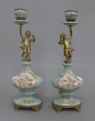 A pair of cherub mounted porcelain candlesticks. 35 cm high.