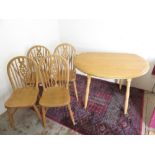 Modern light wood drop-leaf circular table on turned supports, and a set of wheel back dining chairs