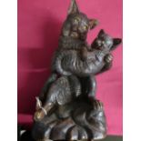 Terracotta model of a seated cat holding a kitten, on rocky base, H40cm