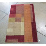 Modern red ground rug decorated with interlocking geometric shapes (180cm x 117cm), a modern rug