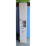 White laminate narrow bathroom cabinet with door above open centre, single drawer and single