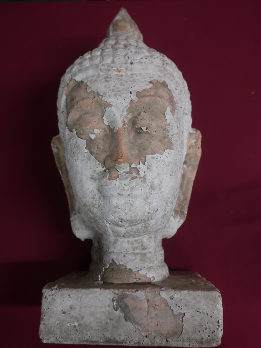 Pottery model of a Tibetan deity head, with remnants of white finish, on a rectangular base, H43cm