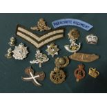 Collection of metal and cloth badges, mainly British, including paratrooper regiment shoulder