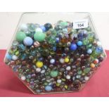 Large hexagonal jar containing a large quantity of marbles of different sizes and designs