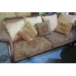 Graduated pair of Regency style country house sofas, with scroll carved back and outswept arms on