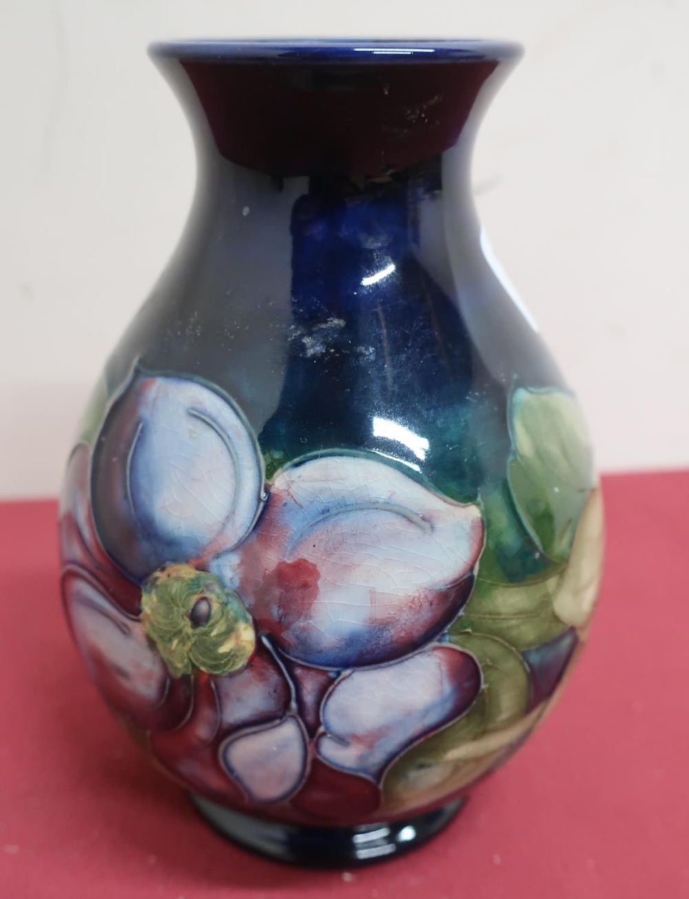 Moorcroft pottery vase, the baluster body decorated with a clematis pattern on a blue ground,