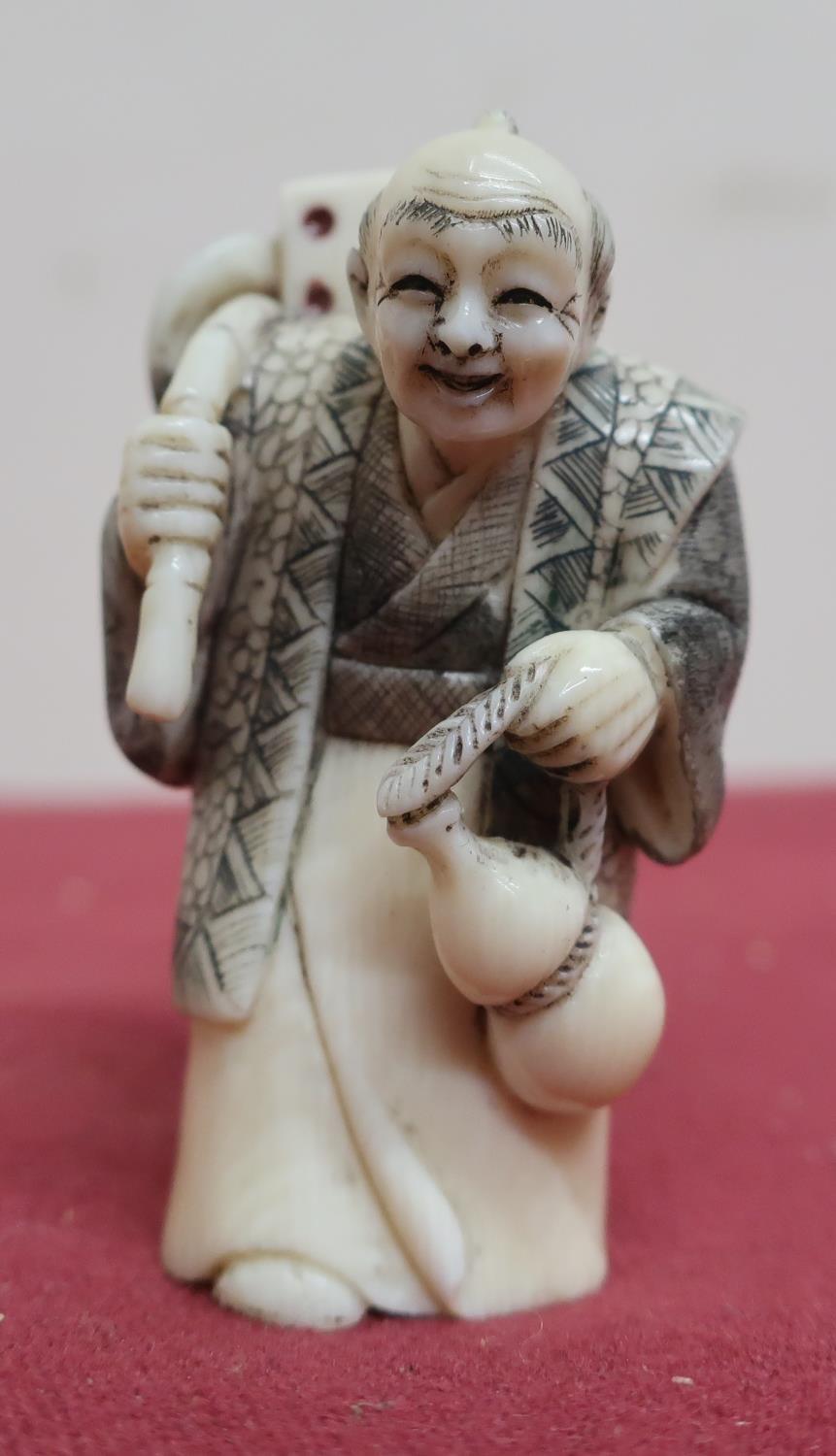 Small late 19th C carved ivory Okimono of a figure carrying a dice, with scratched decoration,