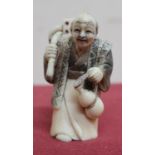 Small late 19th C carved ivory Okimono of a figure carrying a dice, with scratched decoration,