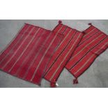 Pair of North African Bedouin type rugs, red ground with striped design and tasselled corners and